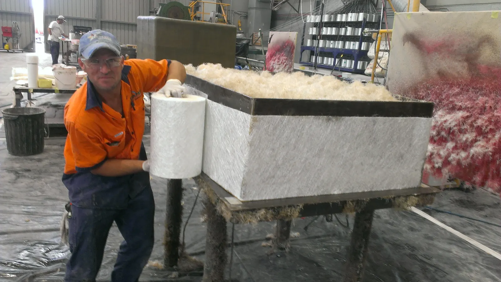 Tradesman laminating glass-fibre mat onto a fibreglass valve pit in the factory