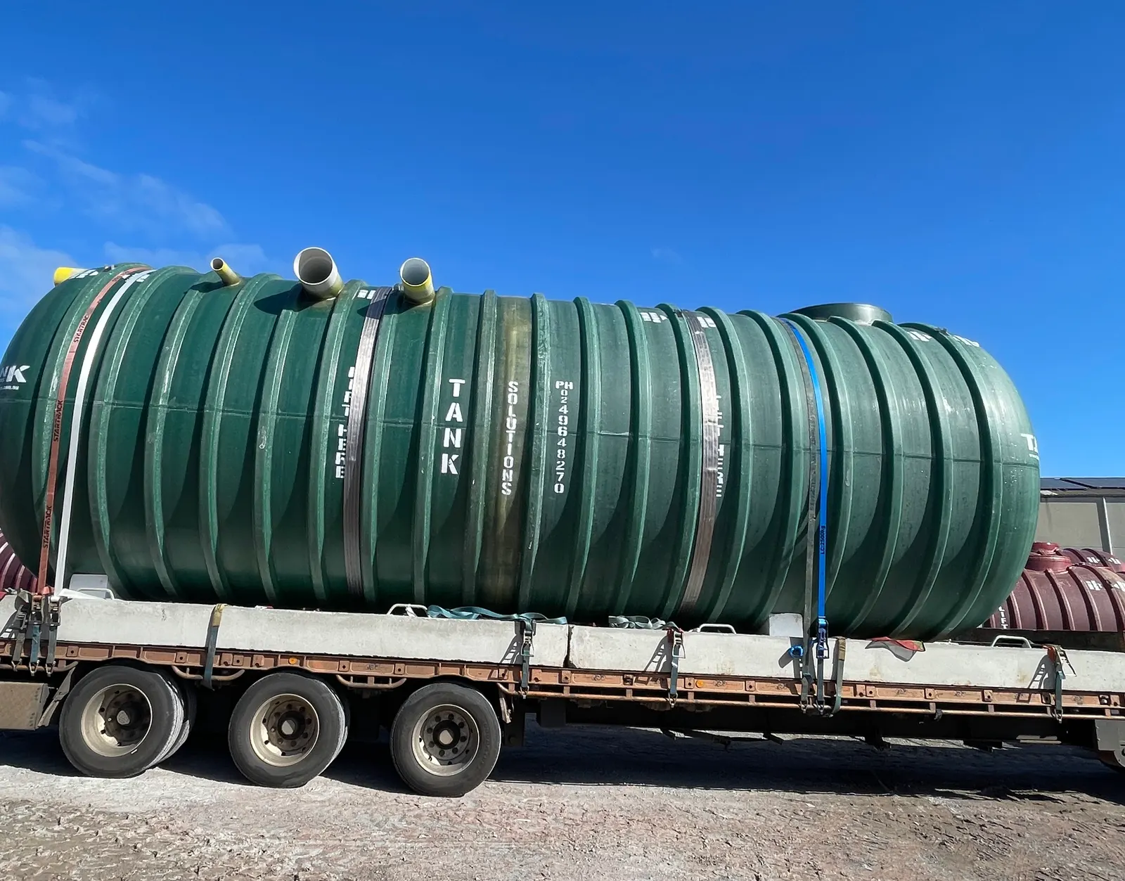 Large ribbed fibreglass water storage tank strapped to a trailer for delivery to Norlane, Victoria
